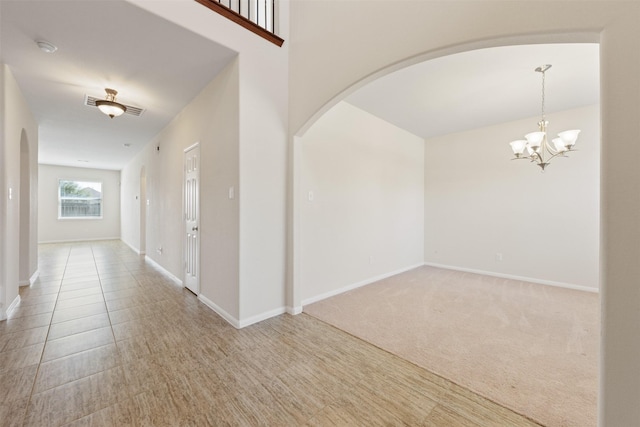 interior space featuring light carpet, baseboards, arched walkways, and a chandelier