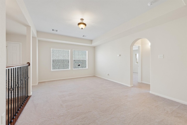 unfurnished room featuring arched walkways, baseboards, visible vents, and light colored carpet