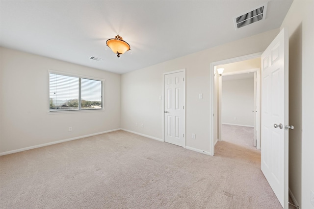 spare room featuring carpet, visible vents, and baseboards