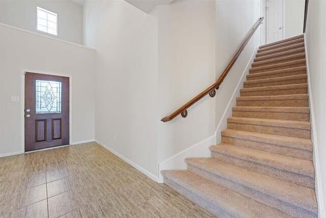 entryway with a towering ceiling, baseboards, and stairs