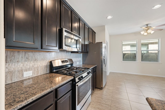 kitchen with appliances with stainless steel finishes, baseboards, dark stone countertops, and tasteful backsplash