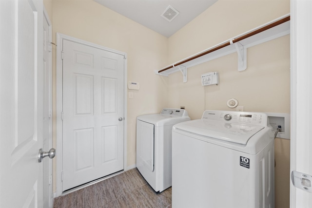 laundry room featuring laundry area, visible vents, wood finished floors, and independent washer and dryer