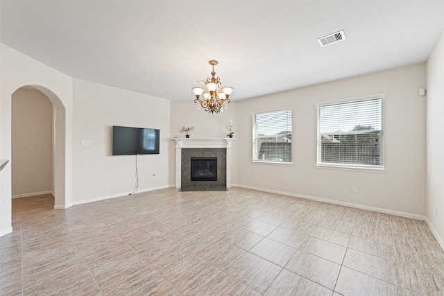 unfurnished living room with arched walkways, a fireplace, visible vents, an inviting chandelier, and baseboards