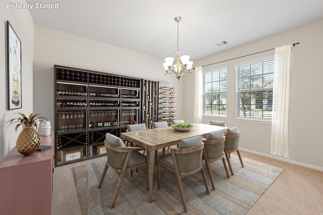 carpeted dining area featuring baseboards, visible vents, and an inviting chandelier