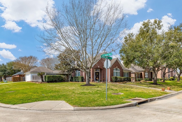 ranch-style home featuring a garage, brick siding, a front lawn, and fence