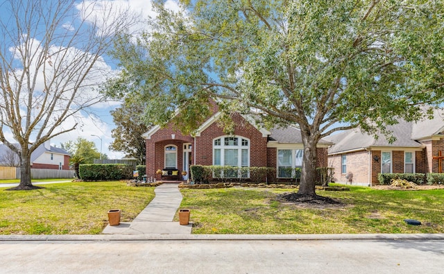 view of front of home with fence, a front lawn, and brick siding