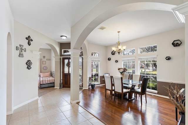 dining area with light wood finished floors, baseboards, visible vents, an inviting chandelier, and ornate columns