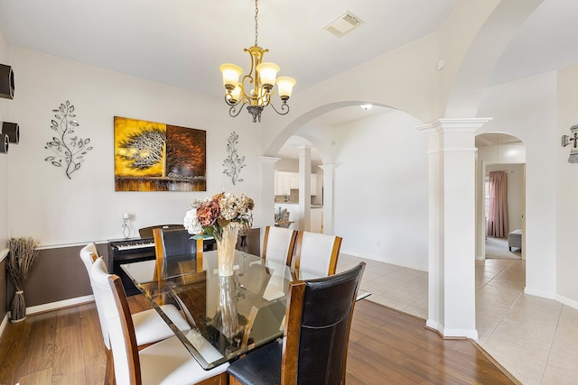 dining room featuring arched walkways, visible vents, and wood finished floors