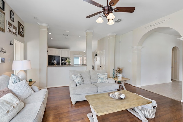 living room featuring arched walkways, recessed lighting, wood finished floors, visible vents, and decorative columns