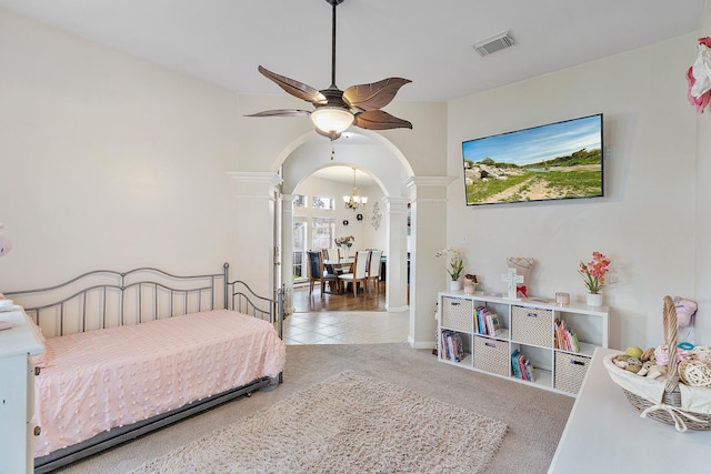 carpeted bedroom featuring ornate columns, visible vents, arched walkways, and ceiling fan with notable chandelier