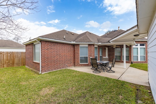 back of property with a yard, a patio area, brick siding, and fence