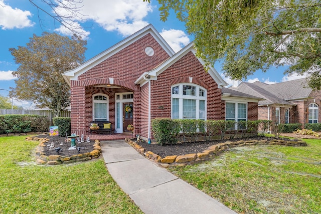 view of front facade with brick siding, a front yard, and fence