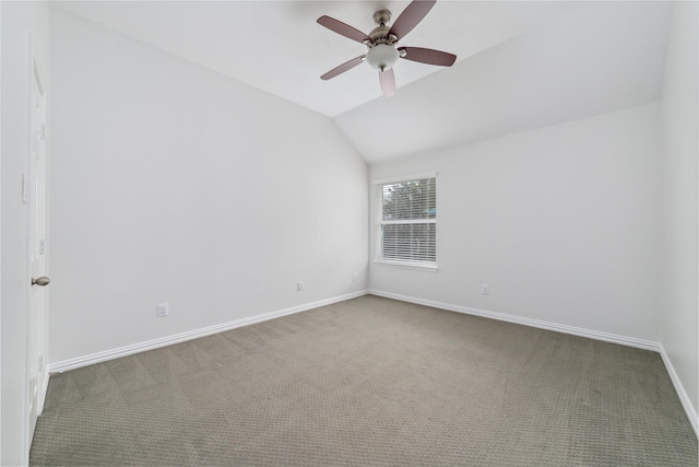 empty room featuring carpet floors, lofted ceiling, ceiling fan, and baseboards