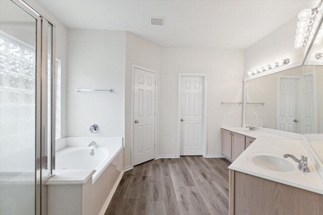 bathroom featuring visible vents, a sink, a garden tub, and wood finished floors