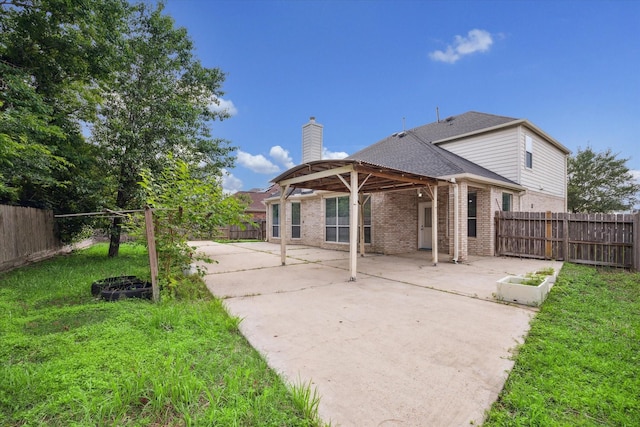 rear view of property featuring a yard, a patio, brick siding, and a fenced backyard