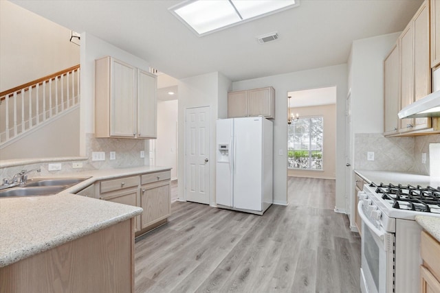 kitchen featuring white appliances, a sink, visible vents, light wood-style floors, and light brown cabinetry