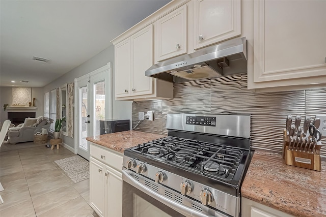 kitchen featuring light tile patterned floors, under cabinet range hood, visible vents, stainless steel gas range, and decorative backsplash