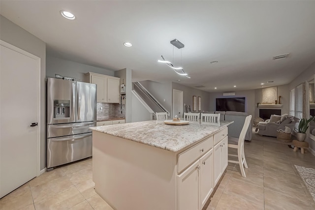 kitchen featuring visible vents, a kitchen island, stainless steel fridge with ice dispenser, and light tile patterned floors