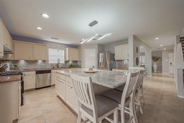 kitchen featuring light tile patterned floors, a sink, visible vents, appliances with stainless steel finishes, and a center island