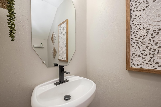 bathroom featuring a textured wall and a sink