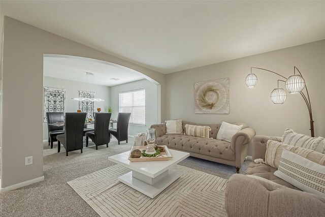 carpeted living area with arched walkways and baseboards