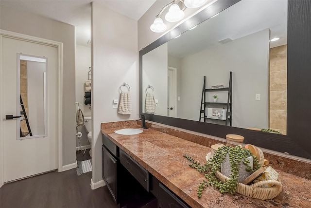 full bathroom with baseboards, visible vents, toilet, wood finished floors, and vanity