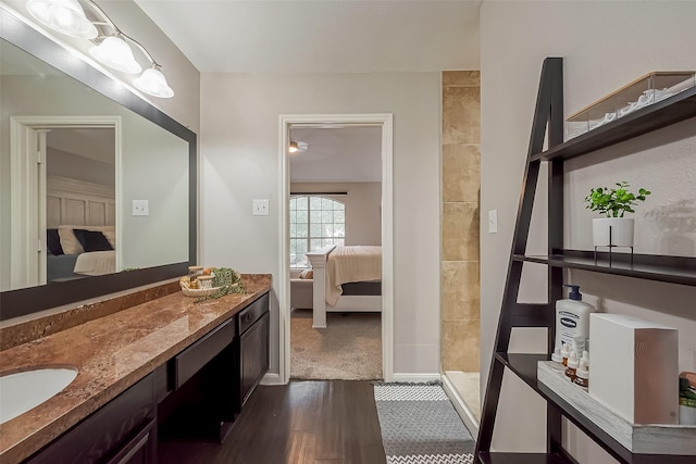 ensuite bathroom featuring a tile shower, wood finished floors, connected bathroom, and vanity