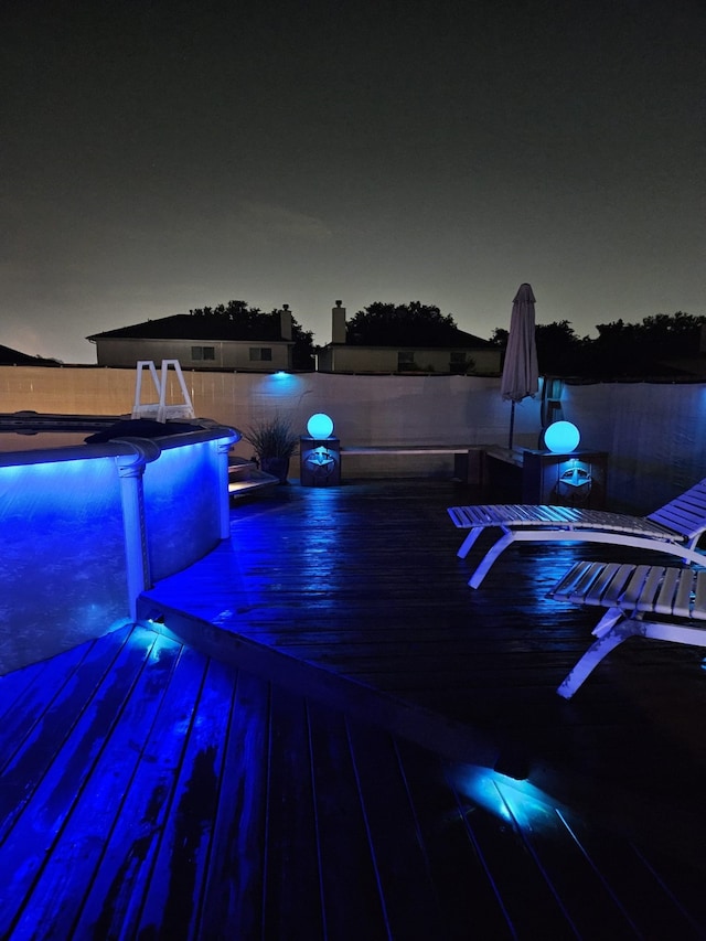 deck at night with fence and an outdoor pool