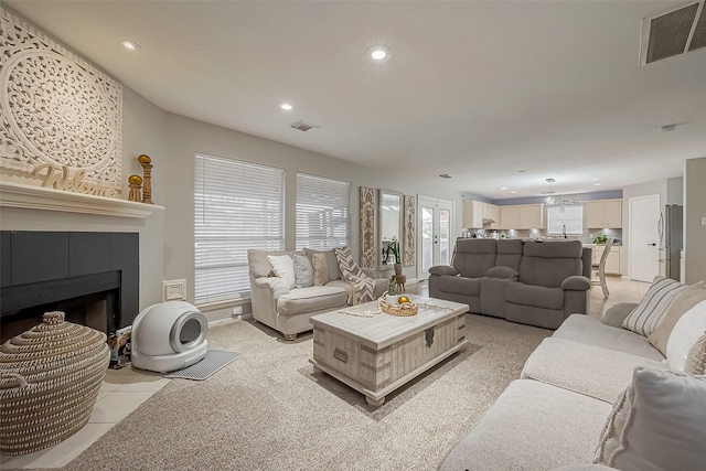 living area with a tile fireplace, visible vents, and recessed lighting