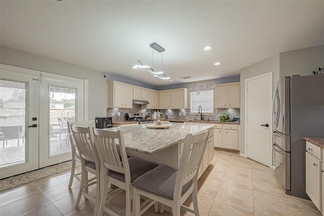 kitchen with light tile patterned floors, stainless steel appliances, backsplash, and a center island