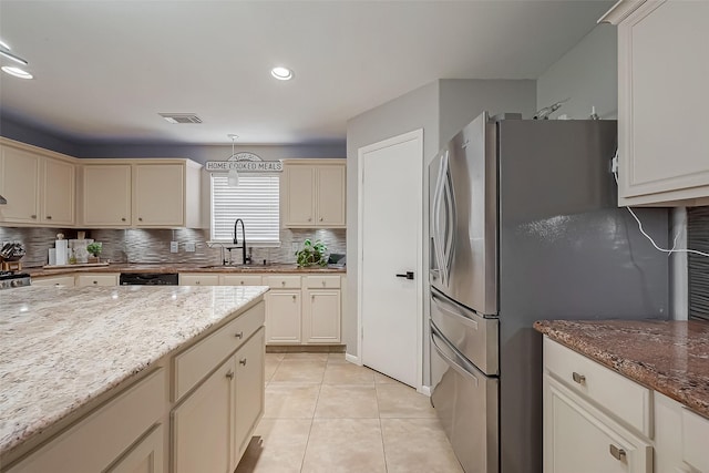 kitchen featuring freestanding refrigerator, cream cabinetry, visible vents, and a sink