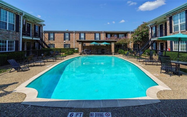 pool featuring stairway, a patio area, and fence