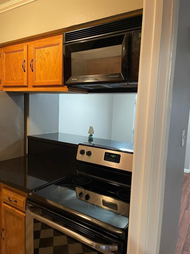 kitchen with electric range, black microwave, and brown cabinetry