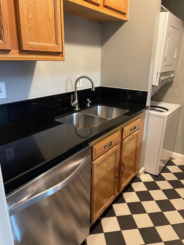 kitchen featuring light floors, dark countertops, brown cabinetry, a sink, and dishwasher