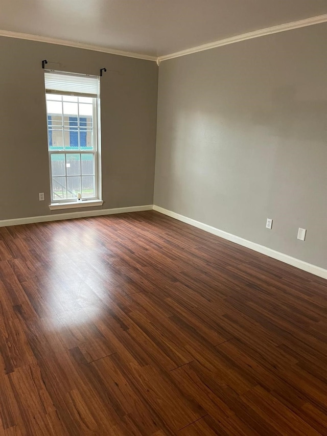 spare room with baseboards, ornamental molding, and dark wood-style flooring