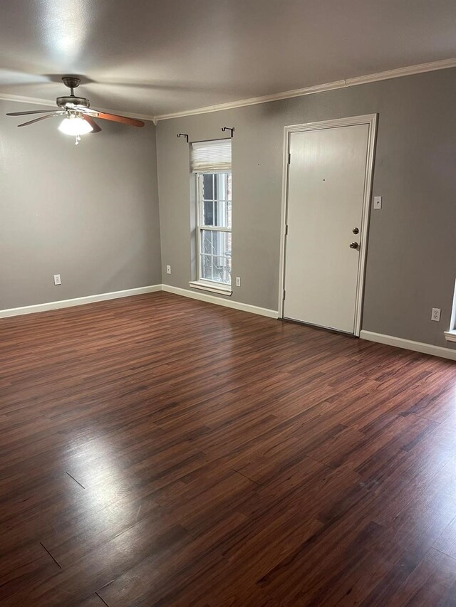 empty room featuring ceiling fan, ornamental molding, dark wood-style flooring, and baseboards