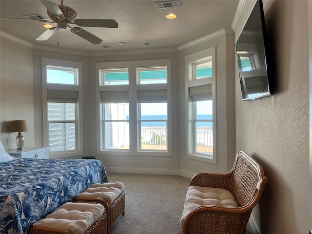 carpeted bedroom with a textured wall, ornamental molding, visible vents, and baseboards