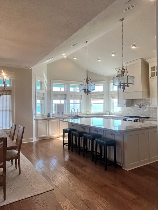 kitchen featuring tasteful backsplash, lofted ceiling, custom range hood, dark wood-style flooring, and white cabinetry