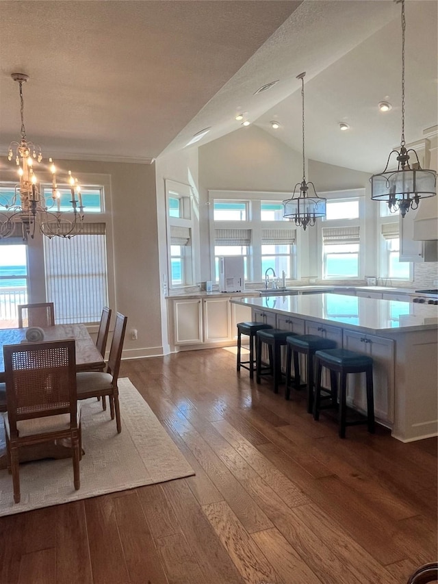 dining space featuring an inviting chandelier, vaulted ceiling, baseboards, and dark wood finished floors