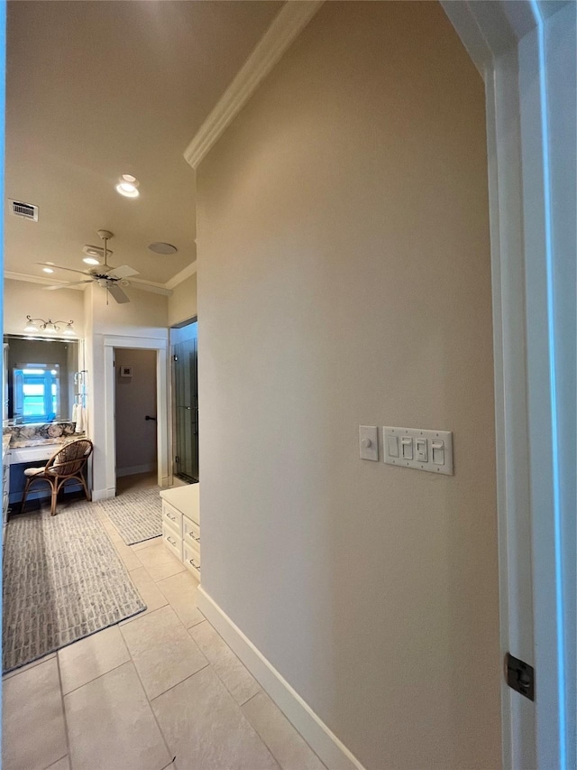 hall with ornamental molding, light tile patterned flooring, visible vents, and baseboards