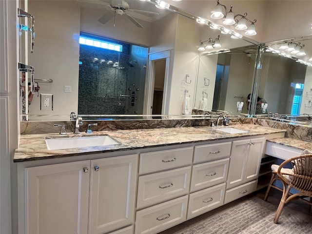 full bath featuring double vanity, a stall shower, a sink, and a ceiling fan