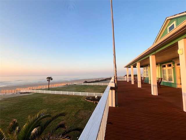 deck at dusk with a yard and a water view