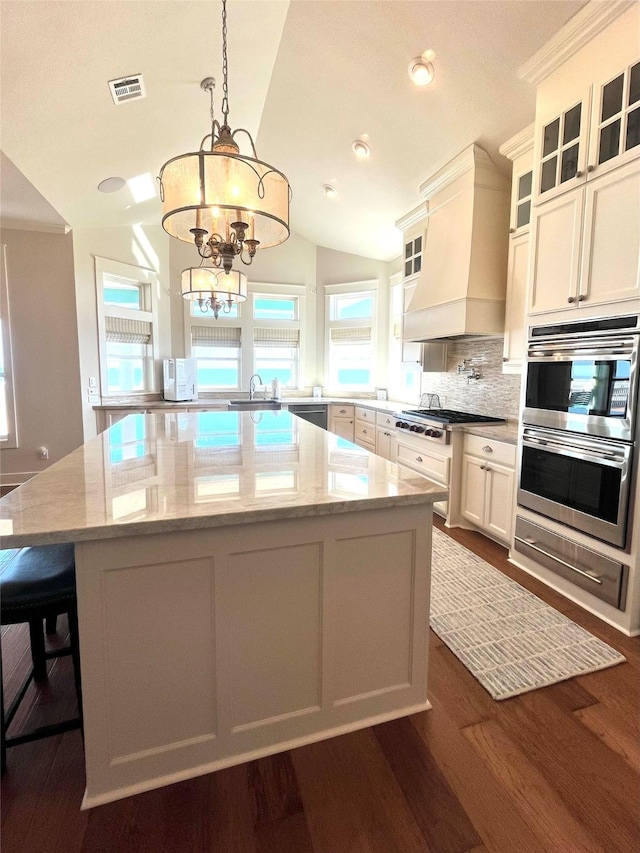 kitchen featuring visible vents, custom range hood, a center island, stainless steel appliances, and a warming drawer