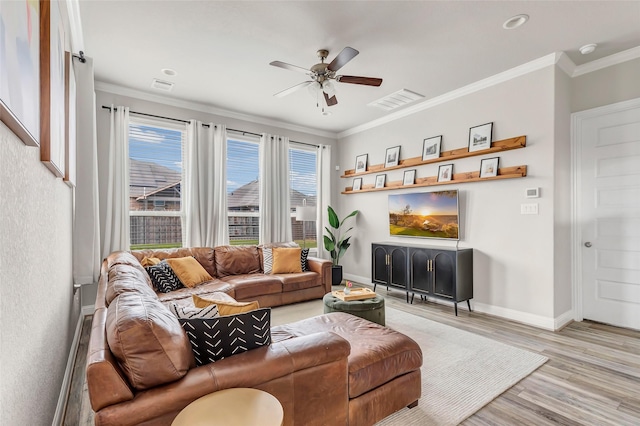 living room with light wood-style floors, baseboards, visible vents, and crown molding