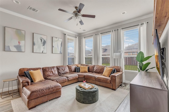 living area with light wood finished floors, visible vents, and ornamental molding