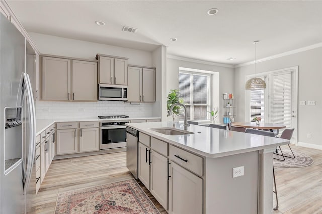 kitchen featuring visible vents, appliances with stainless steel finishes, a breakfast bar, gray cabinetry, and a sink