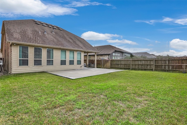 back of house with a shingled roof, fence, a lawn, and a patio