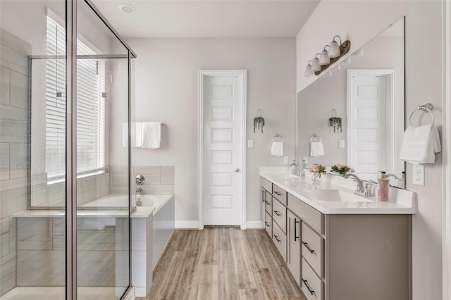 bathroom featuring a bath, a sink, and wood finished floors