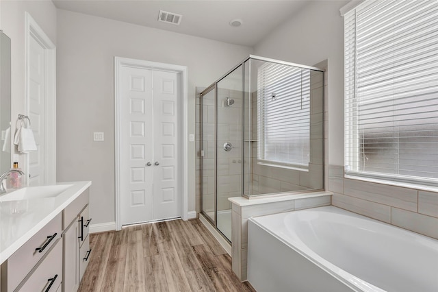 bathroom with a stall shower, visible vents, wood finished floors, vanity, and a bath