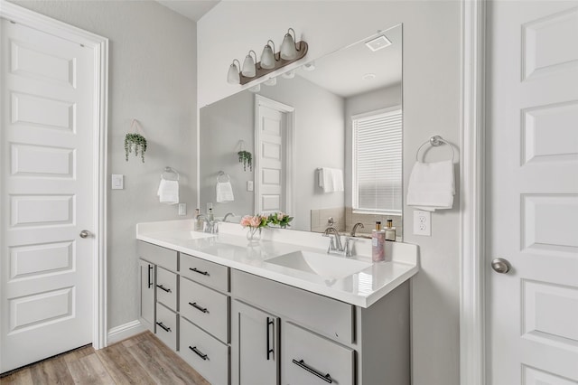 full bathroom with double vanity, visible vents, a sink, and wood finished floors